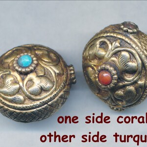 Puede incluir: Dos cuentas redondas de color dorado con intrincados dise&ntilde;os florales. Una cuenta tiene una piedra turquesa en un lado y una piedra de coral en el otro.