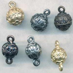 May include: Six ornate metal ball ornaments with decorative designs. The ornaments are in gold, silver, and bronze finishes. Each ornament has a loop for hanging.