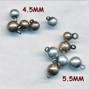 May include: A close-up of two sizes of metal ball ornaments with a loop for hanging. The smaller ornaments are 4.5 mm and the larger ornaments are 5.5 mm. The ornaments are silver and bronze in color.