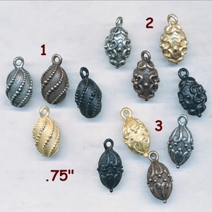 May include: Assortment of 10 metal egg-shaped charms with intricate designs. The charms are in various finishes, including silver, gold, and black. The charms are approximately .75 inches in size.