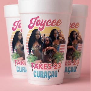 May include: Three white foam cups featuring a graphic print of a person with long dark hair in a bikini. The design includes a yellow and orange sunset, palm trees, and the text Joycee TAKES 23 CURAÇAO in pink and blue lettering.