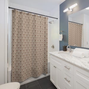 May include: Shower curtain with a beige background and a repeating brown floral pattern. The bathroom features white cabinets, a marble countertop, and a blue wall. The curtain is hanging from a black rod.