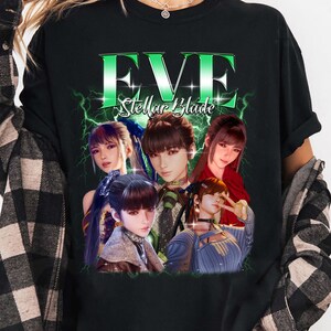 Könnte beinhalten: Schwarzes Langarm-T-Shirt mit einer Grafik von fünf Anime-Charakteren und dem Text "EVE Stellar Blade" in Grün und Weiß. Das Design hat einen Blitz-Effekt. Das T-Shirt wird getragen.