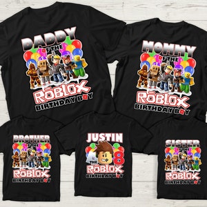May include: Set of five black t-shirts with a Roblox theme. The shirts feature different text, including "Daddy of the Roblox Birthday Boy", "Mommy of the Roblox Birthday Boy", "Brother of the Roblox Birthday Boy", "Sister of the Roblox Birthday Boy", and "Justin of the Roblox Birthday Boy".