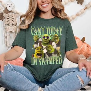 May include: A green t-shirt with a graphic of Shrek and other characters from the movie Shrek. The text on the shirt reads "Can't today I'm swamped".