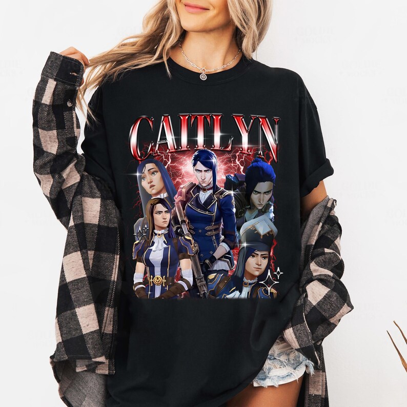 May include: Black t-shirt with a graphic print of a group of characters from the video game League of Legends. The text "Caitlyn" is printed in large, bold letters above the characters.