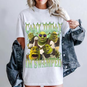May include: White t-shirt with a green Shrek character graphic and the text "CANT TODAY IM SWAMPED".