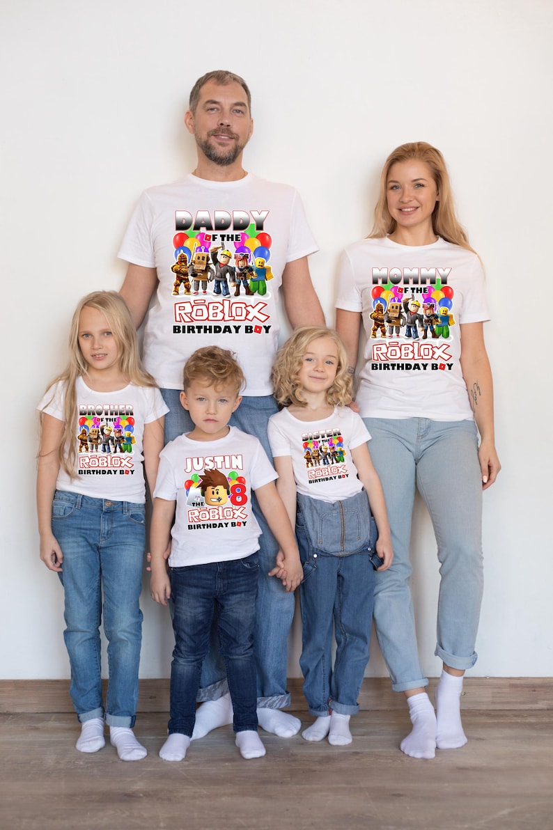 May include: A family of five wearing white t-shirts with a Roblox theme. The shirts feature the text "Daddy of the Roblox Birthday Boy", "Mommy of the Roblox Birthday Boy", "Brother of the Roblox Birthday Boy", "Sister of the Roblox Birthday Boy", and "Justin the Roblox Birthday Boy".
