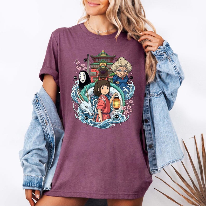 Op de afbeelding: Bordeauxrood T-shirt met een kleurrijke anime-stijl afbeelding. Het ontwerp toont een meisje met een lantaarn, een draak en andere personages. De afbeelding is omgeven door water en kersenbloesems.