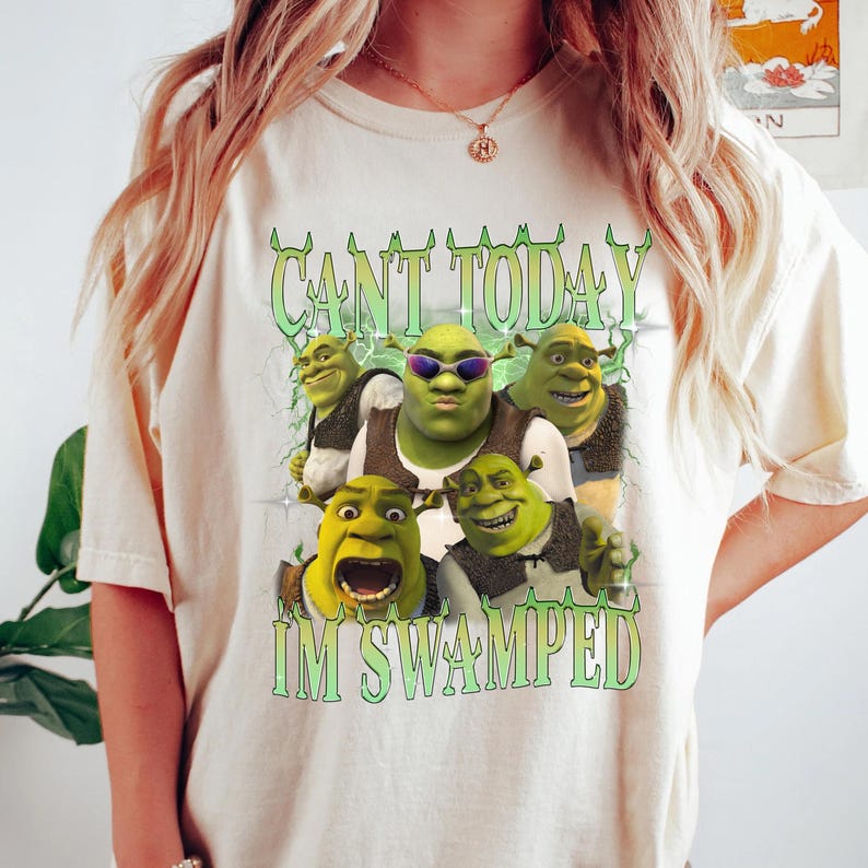 May include: A white t-shirt with a green Shrek character graphic. The graphic features multiple Shrek characters with the text "Can't Today I'm Swamped".