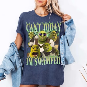 May include: A navy blue t-shirt with a graphic of Shrek and other characters from the Shrek movie franchise. The text on the shirt reads "Can't today I'm swamped".