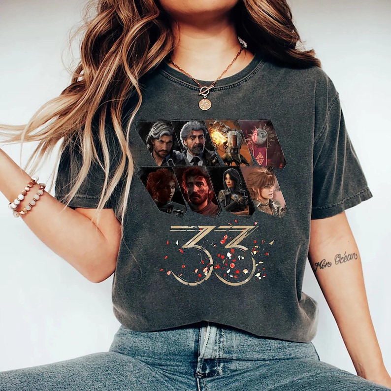 May include: Dark gray t-shirt featuring a collage of character portraits and the number "33" in gold with red and white confetti. The shirt has a vintage, worn look.