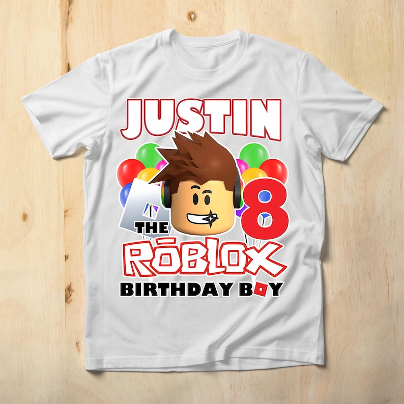 May include: White t-shirt with a red, white, and blue Roblox birthday design. The shirt features a Roblox character, balloons, and the text "Justin the Roblox Birthday Boy".