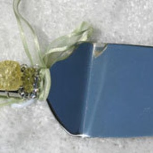 May include: A silver cake server with a handle decorated with yellow and clear gemstone beads.
