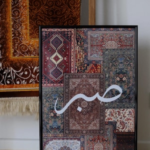 Könnte beinhalten: Ein schwarzer gerahmter Druck mit einer Collage aus bunten gemusterten Teppichen. Der Druck zeigt das arabische Wort "hub" in weißer Kalligraphie.