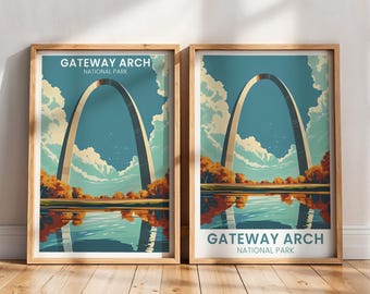 May include: Two framed prints featuring the Gateway Arch National Park. The artwork depicts the arch against a blue sky with clouds, a reflective body of water, and autumn foliage. The text "Gateway Arch National Park" is displayed at the top and bottom of the prints.