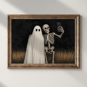 Peut inclure: Une impression d'art encadr&eacute;e repr&eacute;sentant un fant&ocirc;me blanc et un squelette humain debout ensemble dans un champ d'herbes hautes dor&eacute;es sur fond sombre. Le squelette tient un smartphone noir pour prendre un selfie avec le fant&ocirc;me.