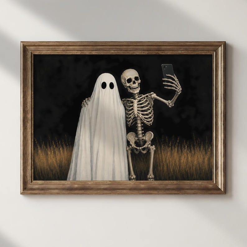 Peut inclure: Une impression d'art encadr&eacute;e repr&eacute;sentant un fant&ocirc;me blanc et un squelette humain debout ensemble dans un champ d'herbes hautes dor&eacute;es sur fond sombre. Le squelette tient un smartphone noir pour prendre un selfie avec le fant&ocirc;me.
