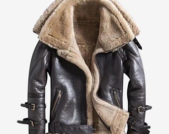 May include: A black leather jacket with a shearling collar and lining. The jacket features a zip closure, multiple pockets, and adjustable straps on the sleeves and waist. The jacket has a classic aviator style.