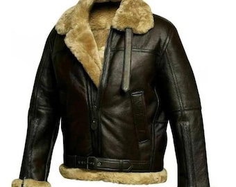May include: A dark brown leather jacket with a tan shearling collar and lining. The jacket features a zip-up front, a buckled belt at the waist, and shearling trim on the cuffs. The jacket has a classic aviator style.