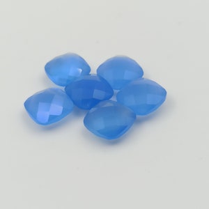 May include: Six light blue, square-cut gemstones are arranged in a cluster. Each gem has a faceted surface, catching the light and creating a sparkling effect. The gems are a soft, translucent blue, suggesting a delicate quality.