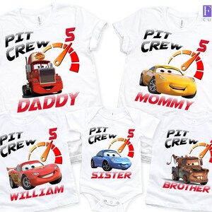 May include: White t-shirts and a onesie featuring cartoon race cars and the text "PIT CREW" with the number "5". Each shirt has a different character and name: "DADDY", "MOMMY", "WILLIAM", "SISTER", and "BROTHER".