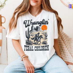 Wranglin Feral Children Shirt, Cowboy Riding Graphic Tee, Funny Western Desert T-Shirt, Vintage Country Cactus Sunset Design