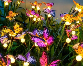 May include: A collection of colorful butterfly-shaped solar garden lights. The butterflies have vibrant wings in shades of yellow, orange, pink, and purple. Each light has a small, round, glowing bulb.