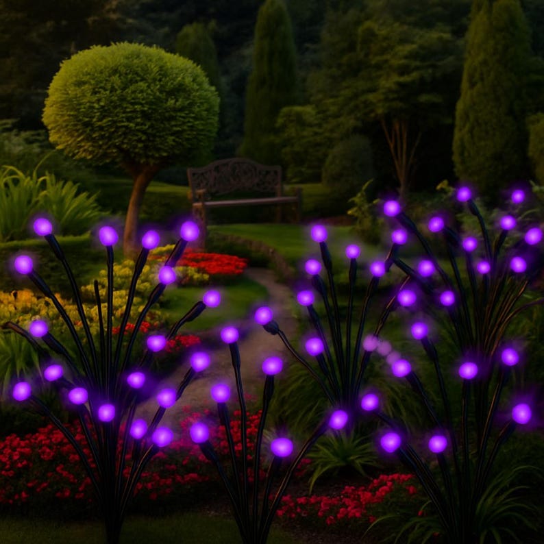 May include: Outdoor garden lights with purple LED bulbs. The lights are arranged in clusters, resembling small bushes. The black stems contrast with the vibrant purple glow, creating a decorative lighting effect. The lights are set in a garden with a bench and a walking path.