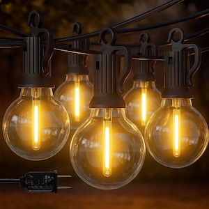 May include: String of outdoor globe string lights. Each light has a clear, round bulb with a warm yellow glow. The bulbs are connected by a black wire and have a black fixture. A black plug is visible at the end of the string.