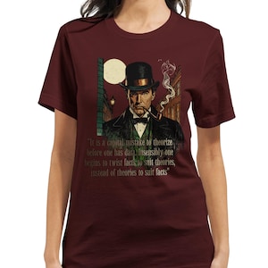 May include: Burgundy t-shirt featuring a detailed illustration of a man in a top hat smoking a pipe, with a quote about data and theories. The artwork includes a cityscape and a full moon. The shirt is a solid color.