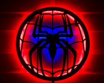 May include: A red and blue LED light shaped like a spider web with a black spider silhouette in the center.