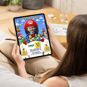 May include: A digital invitation for a Super Mario themed birthday party for a child named Thomas turning 7. The invitation features a photo of the birthday boy in a Mario costume, along with the text "Super Thomas Turn 7" and details about the party, including the date, time, and location.