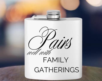 Może przedstawiać: Biała, stalowa butelka na alkohol z czarnym napisem "Pairs well with FAMILY GATHERINGS".