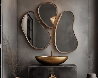May include: A modern bathroom vanity with a gold sink and a unique, abstract mirror. The vanity is made of dark metal and has a gold butterfly-shaped handle. The room is decorated in a minimalist style with a dark gray wall and a gold vase.