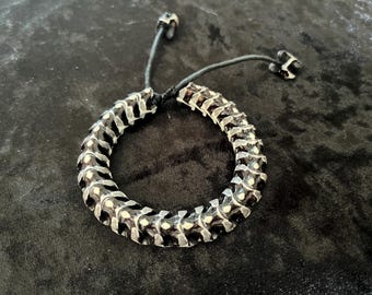 Pulseira rígida preta e branca com contas de espinha dorsal de osso de cobra.