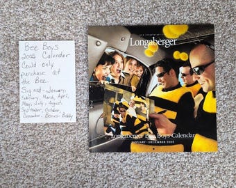 May include: A Longaberger Bee Boys 2005 calendar with a photo of people in bee-themed outfits. The calendar includes the months January to December. A handwritten note says "Could only purchase at the Bee."
