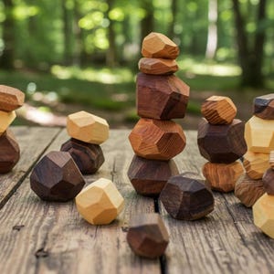 May include: Wooden geometric stacking blocks in various shades of brown and tan are arranged on a weathered wooden surface. Some blocks are stacked, while others are scattered, creating a playful and natural aesthetic. The background is a blurred green forest.