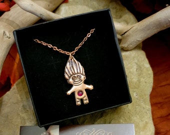 May include: A copper troll pendant necklace with a red gemstone in the belly. The necklace is in a black box with a business card that reads "Handcrafted Chainmaille Jewelry and Art Tangled Earth Arts Addy Neilson TangledEarthArts.com Etsy.com/shop/TangledEarth"