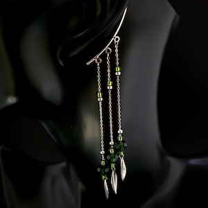 May include: Silver ear cuff with three dangling chains adorned with green crystal beads and silver leaf charms.
