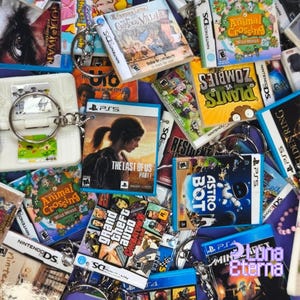 Può includere: Una collezione di portachiavi di videogiochi con vari titoli popolari, tra cui The Last of Us, Animal Crossing, Grand Theft Auto, Astro Bot e Plants vs. Zombies. I portachiavi sono realizzati in plastica e presentano grafiche e testo colorati.