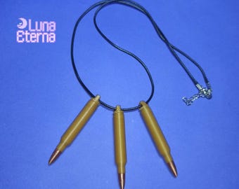 Può includere: Una collana con cordoncino nero con tre ciondoli a forma di proiettile dorati. La collana ha una chiusura argentata.