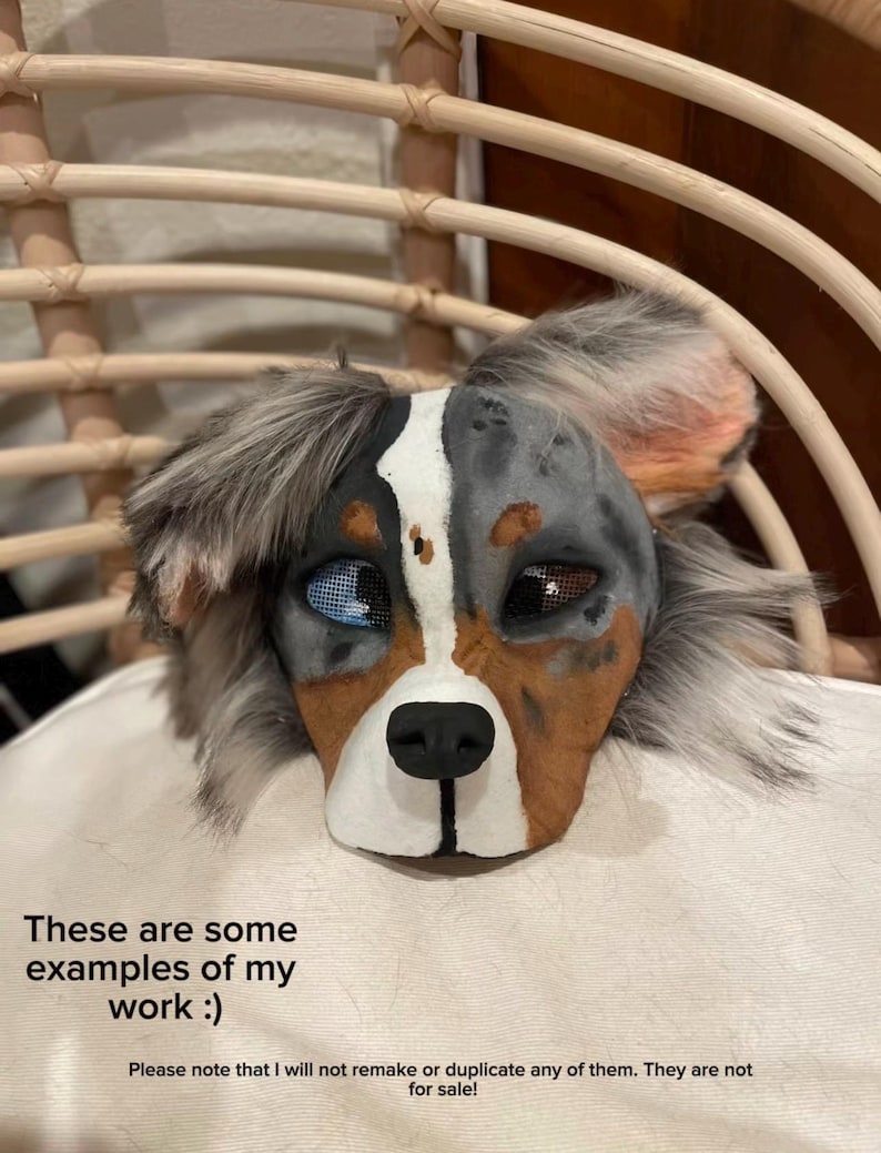 May include: A detailed dog mask with blue, brown, and gray fur, featuring a white stripe down the center of the face. The mask has realistic eyes and a black nose. Text on the image reads: "These are some examples of my work :)"