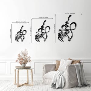 K&ouml;nnte beinhalten: Drei Gr&ouml;&szlig;en von Wandkunst aus Metall, die ein Paar zeigt, das eine dampfende Tasse Kaffee h&auml;lt. Die Kunst ist im minimalistischen Stil mit schwarzen Linien auf wei&szlig;em Hintergrund gehalten. Die Gr&ouml;&szlig;en sind 30 cm x 45 cm, 41 cm x 60 cm und 51 cm x 75 cm.