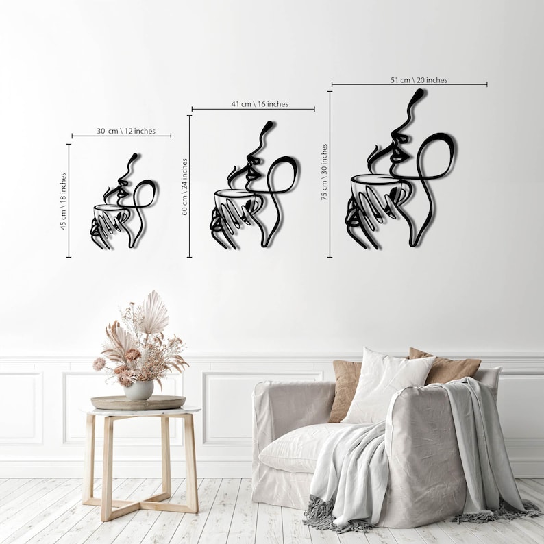 K&ouml;nnte beinhalten: Drei Gr&ouml;&szlig;en von Wandkunst aus Metall, die ein Paar zeigt, das eine dampfende Tasse Kaffee h&auml;lt. Die Kunst ist im minimalistischen Stil mit schwarzen Linien auf wei&szlig;em Hintergrund gehalten. Die Gr&ouml;&szlig;en sind 30 cm x 45 cm, 41 cm x 60 cm und 51 cm x 75 cm.