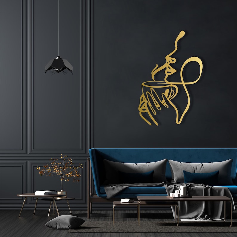K&ouml;nnte beinhalten: Goldene Wandkunst aus Metall, die eine stilisierte Frau darstellt, die eine Tasse Kaffee mit aufsteigendem Dampf h&auml;lt. Die Kunst ist an einer schwarzen Wand in einem modernen Wohnzimmer angebracht.