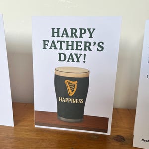 May include: A white ceramic mug with a black handle and the text "But First, Coffee" in a bold, black font. The mug is filled with a dark liquid, likely coffee, and sits on a light-colored surface.