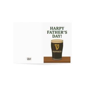 May include: A Father's Day greeting card featuring a pint of stout with a creamy head. The card reads "HARPY FATHER'S DAY!" above the pint and "HAPPINESS" below. The pint glass has a gold harp logo.