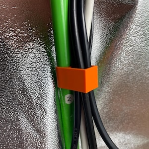 Könnte beinhalten: Ein orangefarbener Kabelbinder, der vier Kabel zusammenhält, darunter ein grünes Kabel mit der Nummer "2" darauf.