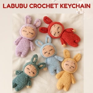 Może przedstawiać: Kolekcja ręcznie robionych breloków do kluczy w kształcie królika. Breloki są w różnych kolorach, w tym fioletowym, czerwonym, niebieskim, zielonym i żółtym. Tekst "LABUBU CROCHET KEYCHAIN" znajduje się na górze obrazu.